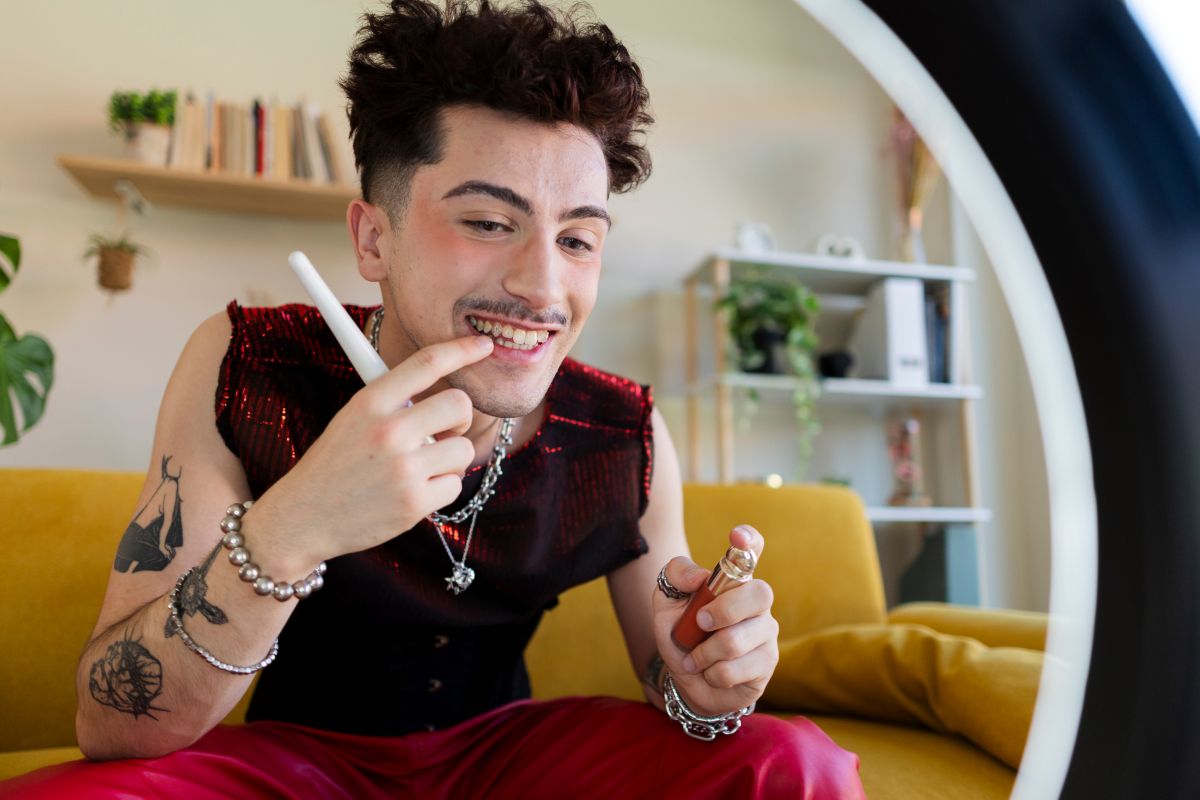 young man applies makeup in front of phone